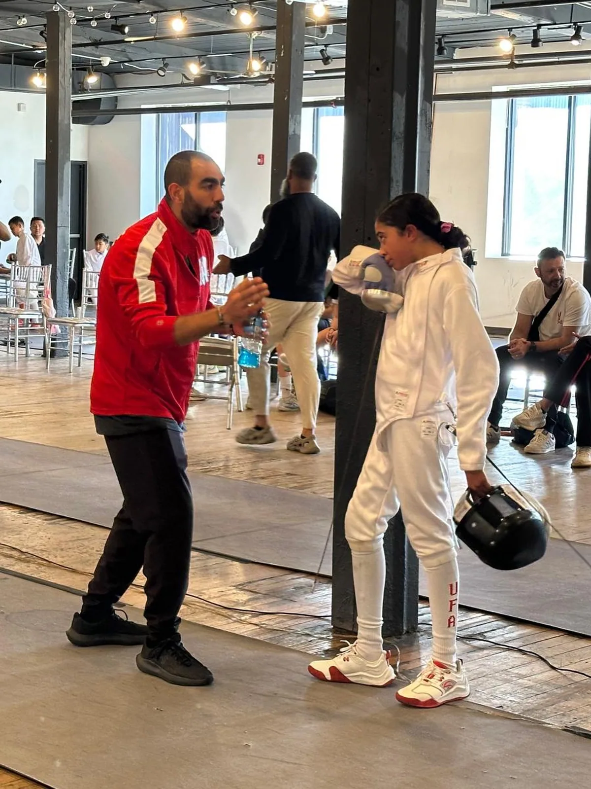 Head coach giving strategy instructions to a student fencer before a bout